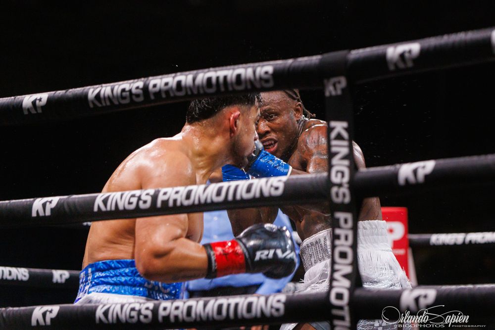 Two boxers exchange punches in a King's Promotions boxing match inside a professional ring.
