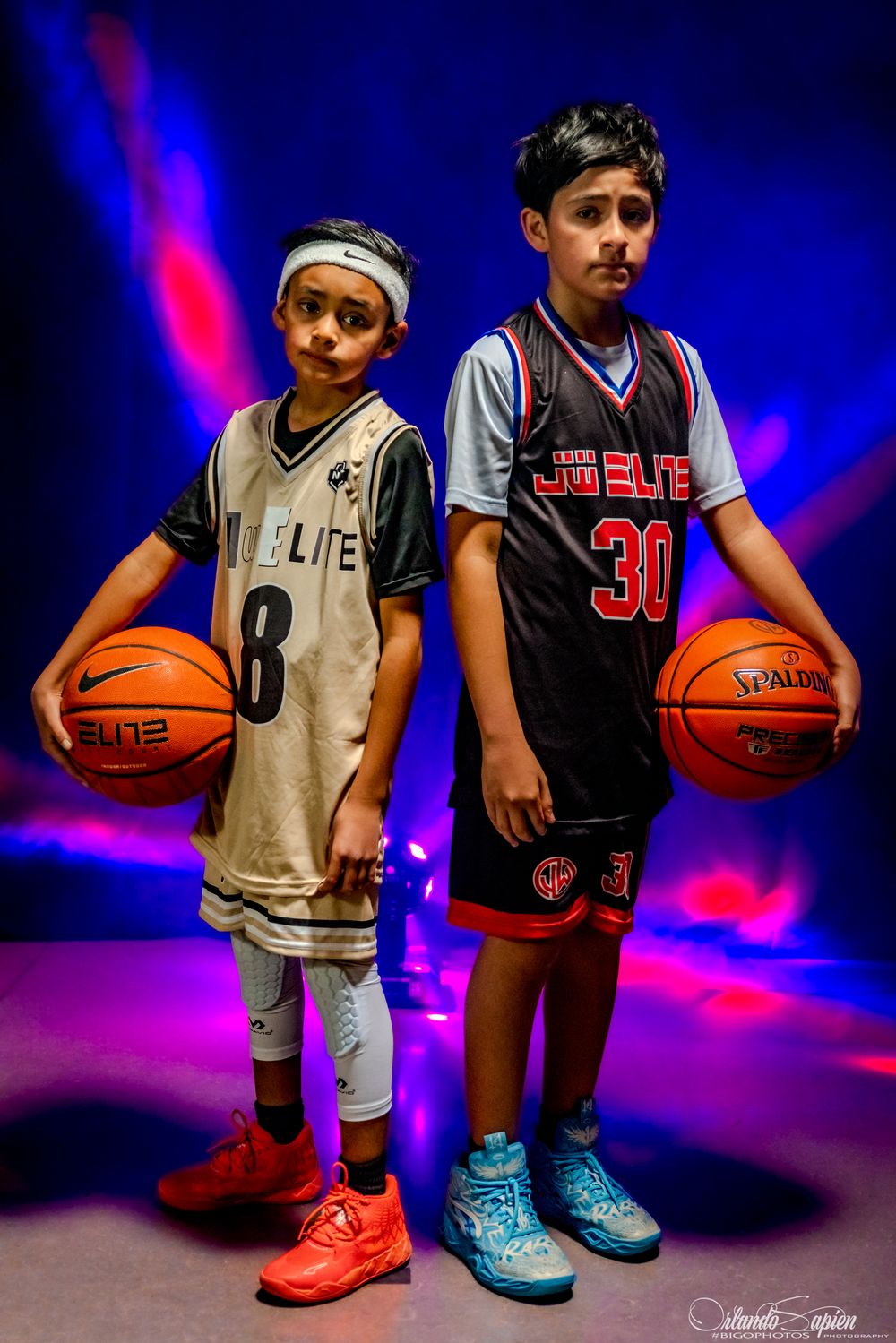 Youth basketball players pose with basketballs against dramatic blue and purple lighting backdrop.
