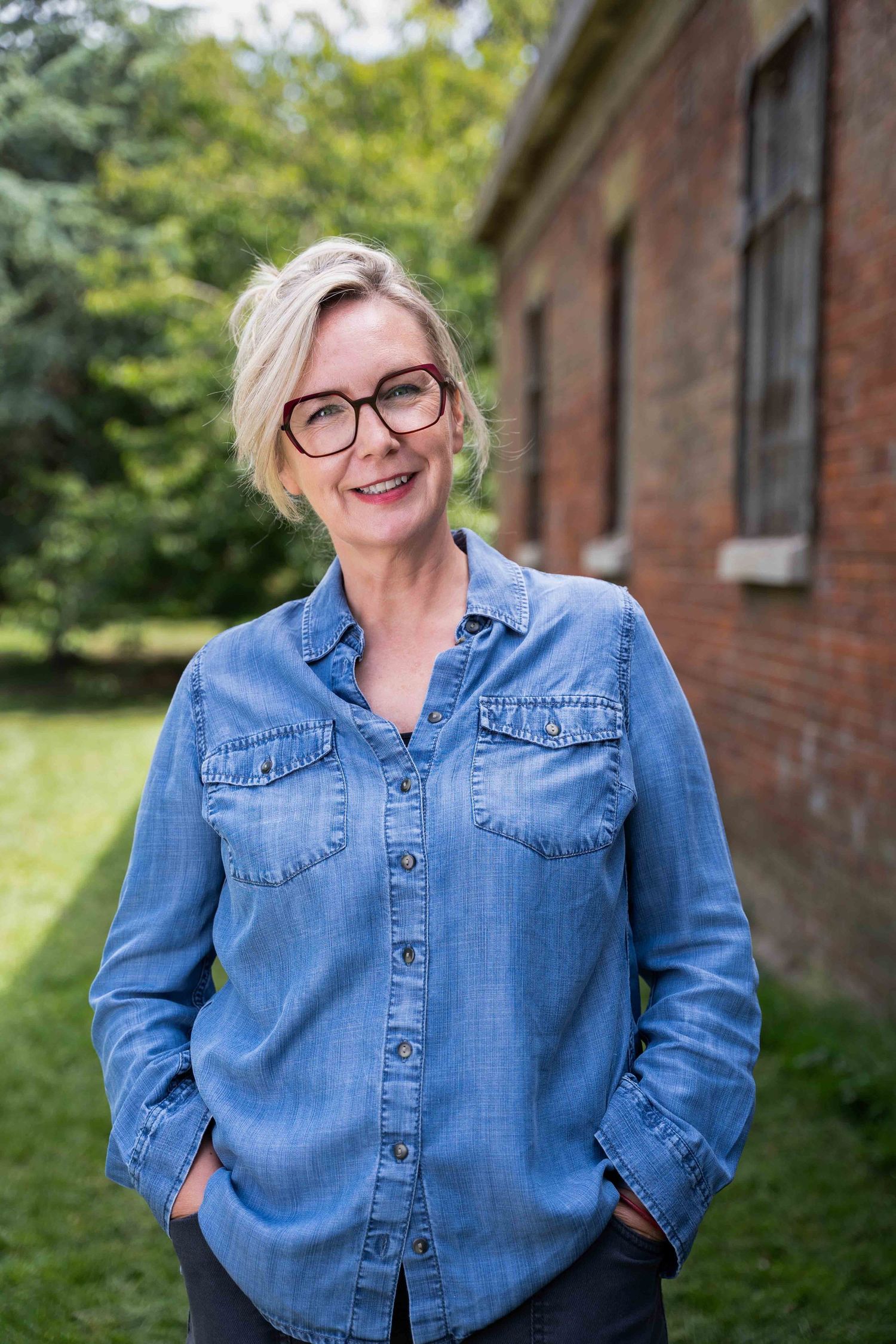 Personal branding portrait of a Portsmouth-based business consultant. She wears a blue denim shirt and glasses and is smiling