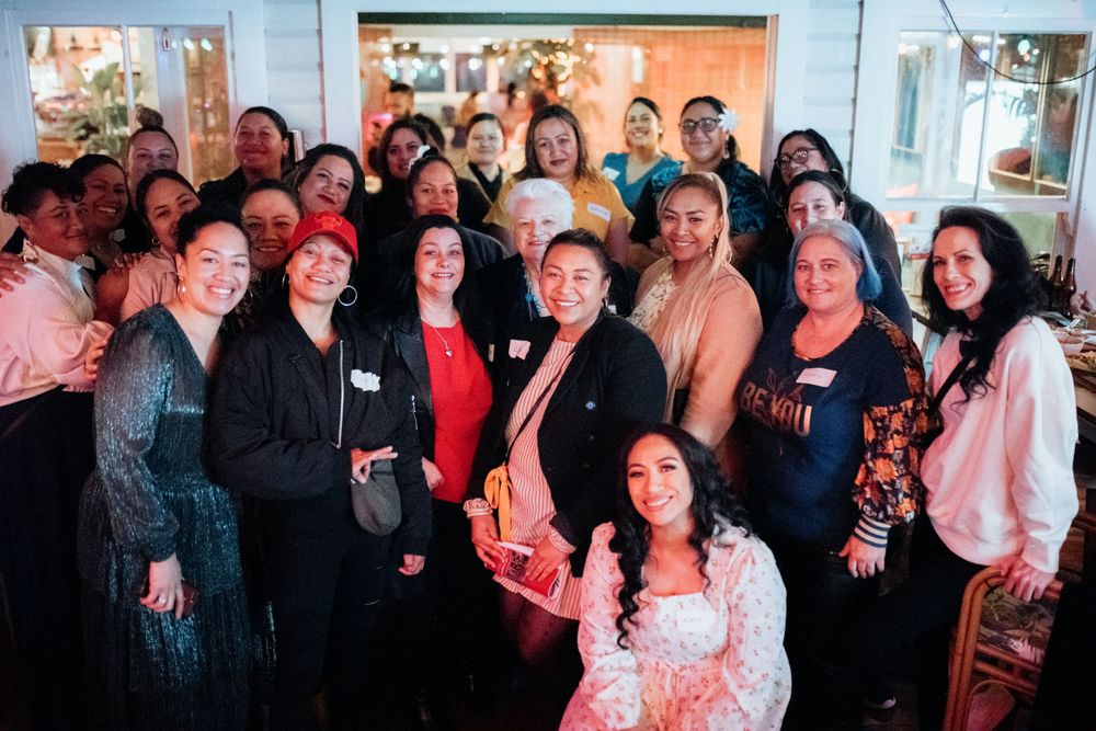 Large group of diverse women smiling together at a festive indoor gathering or networking event.