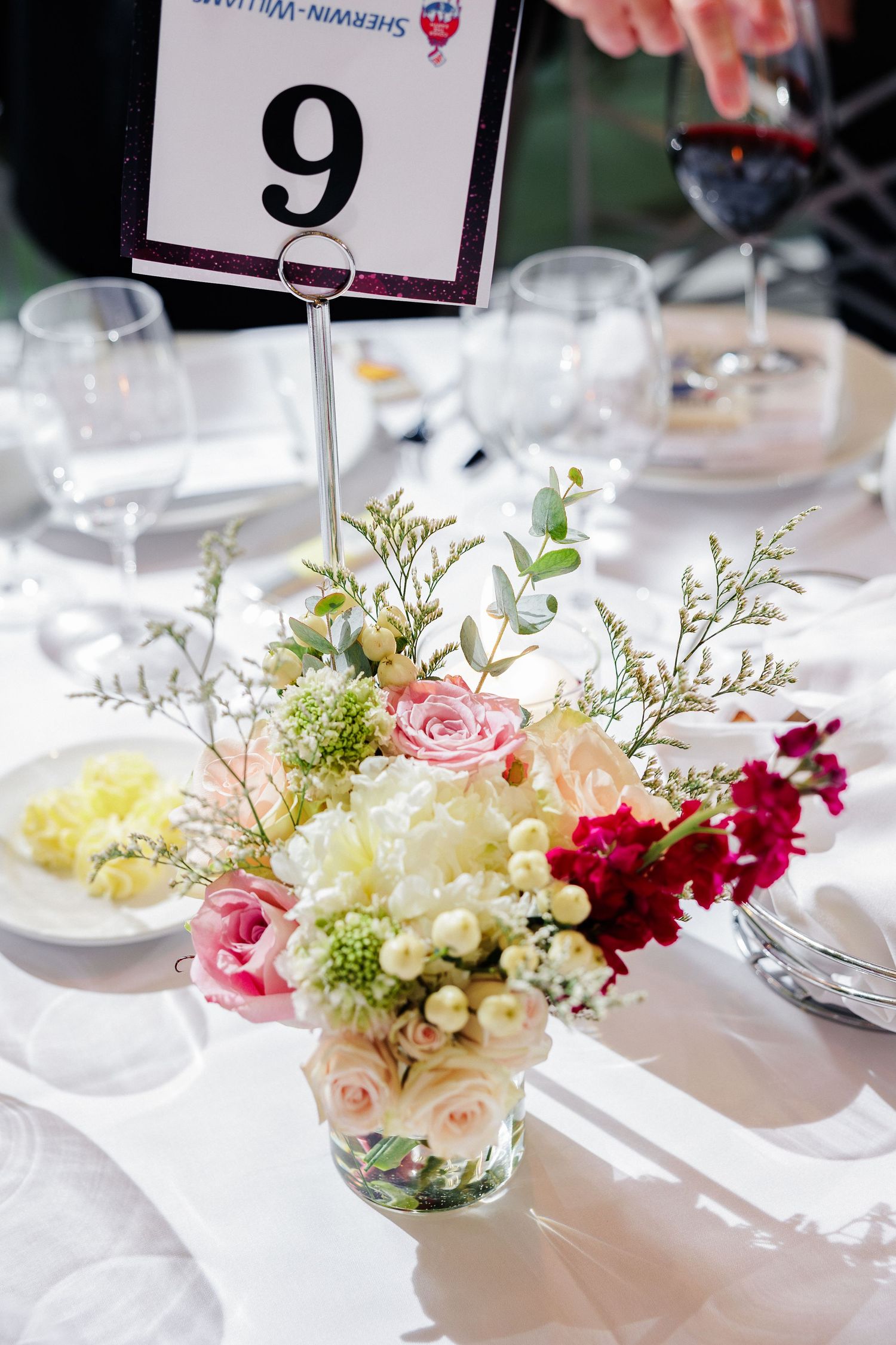 Elegant dinner table setting and a delicate floral centerpiece of pink roses and mixed flowers.