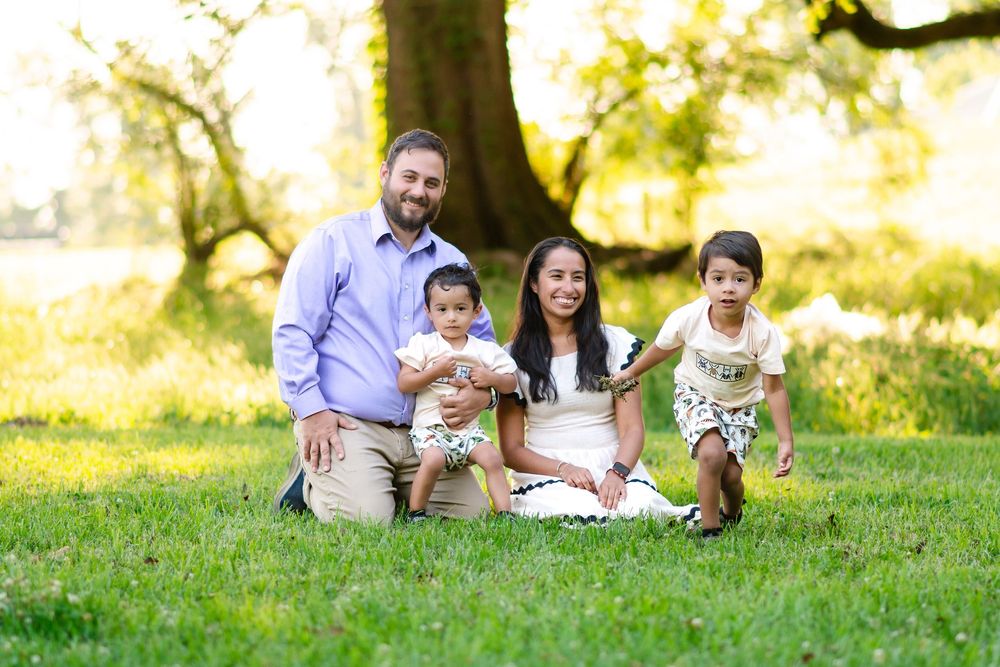 young family sitting and smiling while their son runs around