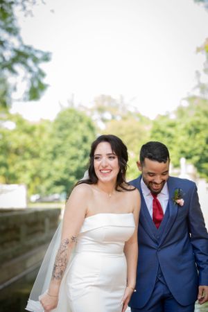 Happy newlyweds share a candid laughing moment in their wedding attire.