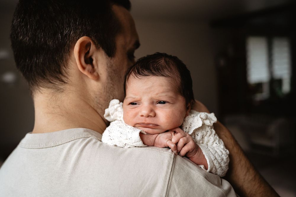 A tender moment between parent and baby in a series of black and white photos showing gentle embrace and comfort.