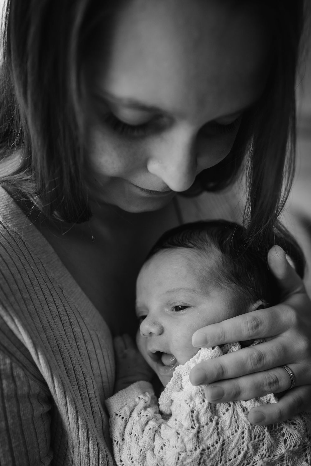 A tender black and white photo series showing a parent gently kissing their baby's forehead in multiple frames.