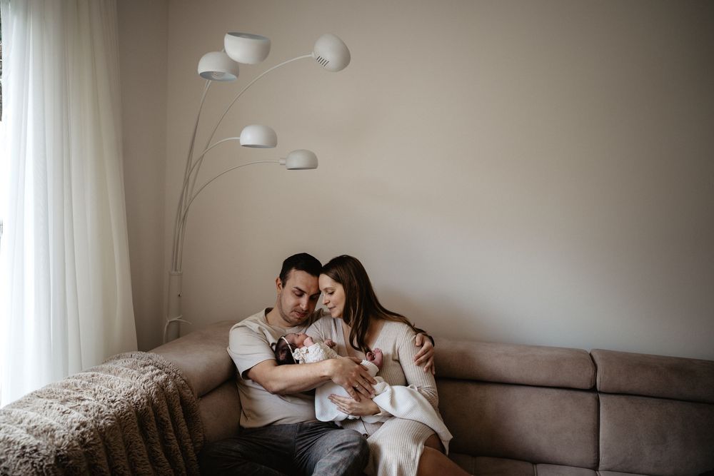 A couple relaxes together on a gray couch in a bright modern living room with white walls.