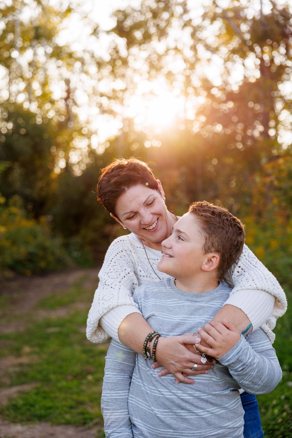 A tender embrace between parent and child captured in golden sunlight during an outdoor photo session.