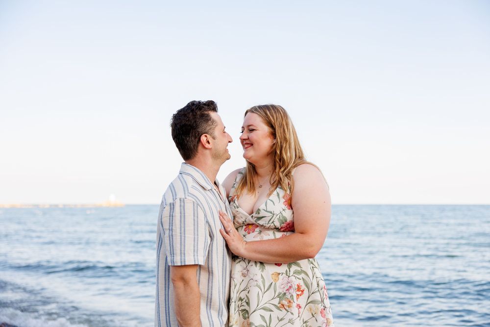 A romantic couple shares tender moments on a sunny beach with ocean waves in the background.