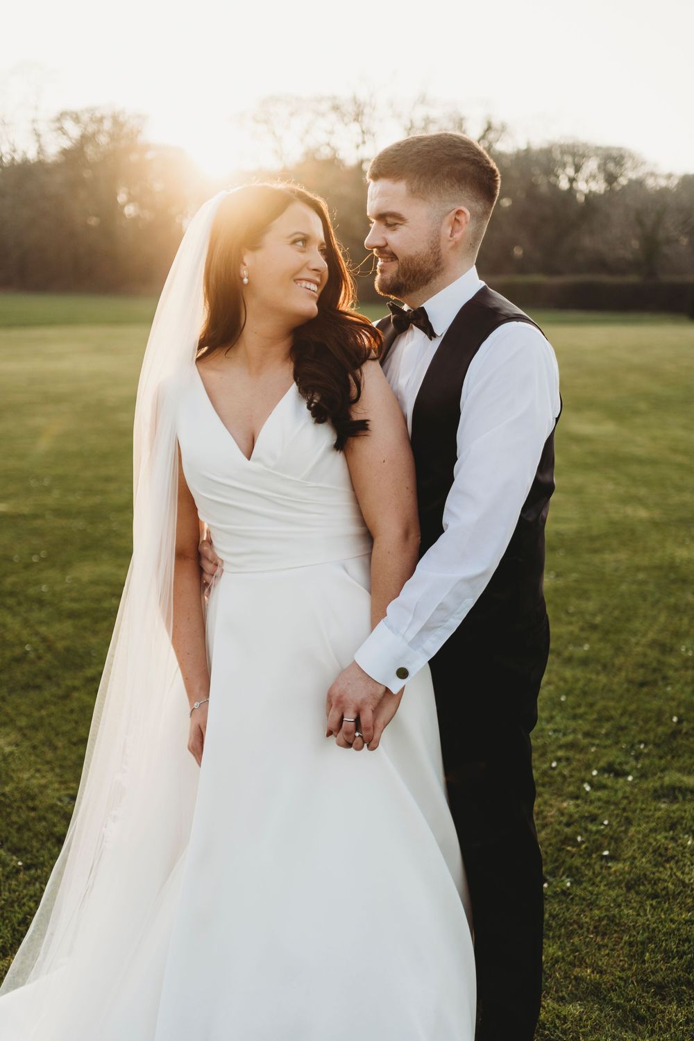 Wedding couple at golden hour backlit by the setting sun.
