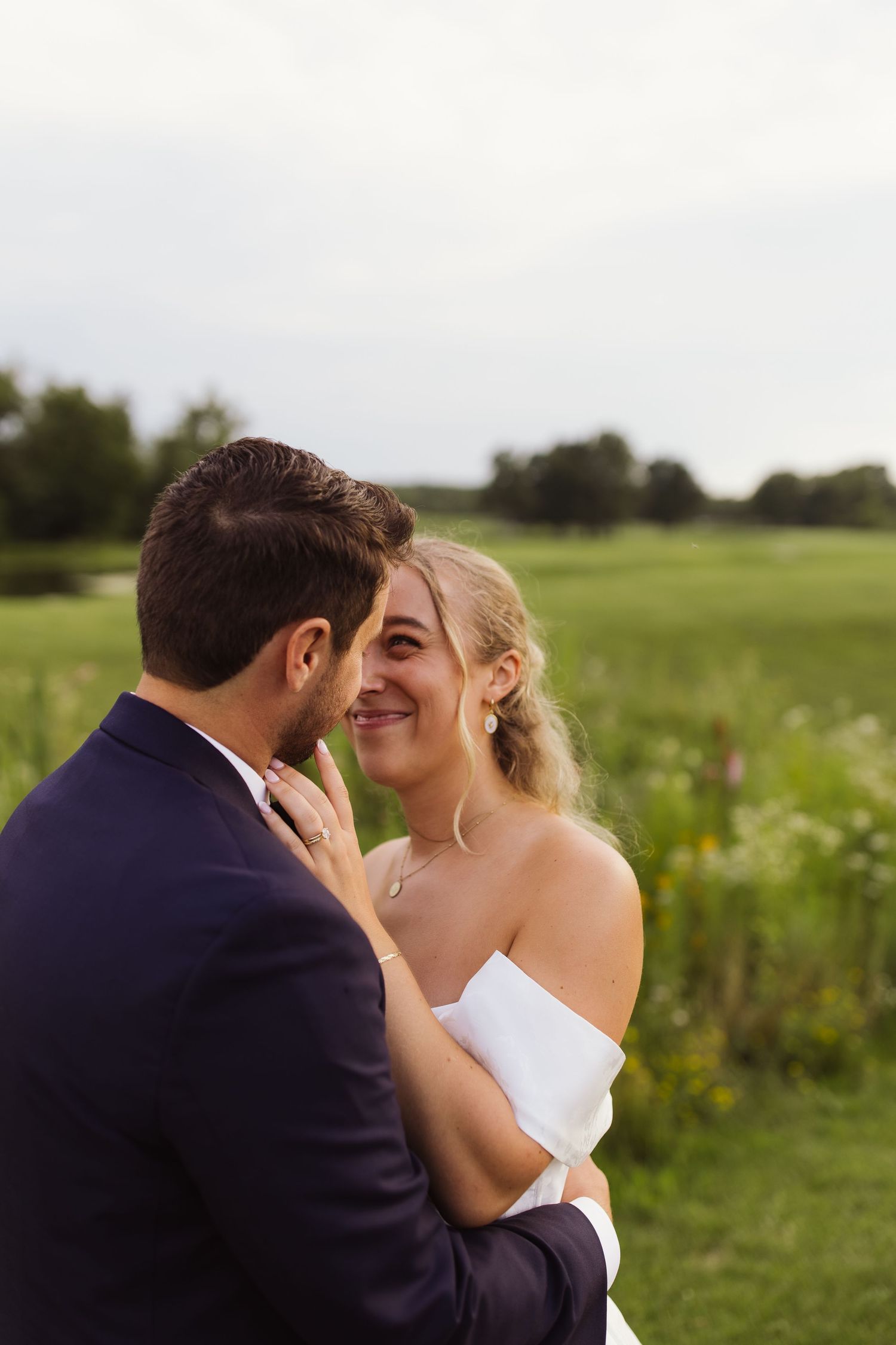 A bride in white laughs joyfully while speaking with nuns outside a church building.