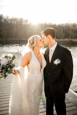 Romantic sunset wedding portraits on a lakeside dock with golden light.