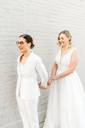 Candid moments captured against a white brick wall in matching white outfits.