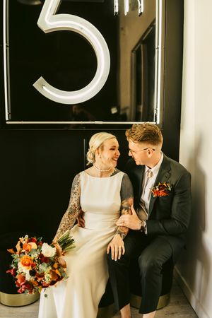 A couple shares an intimate moment beneath a large number 5 sign.