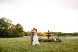 A romantic sunset wedding portrait with a fountain in the background.