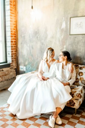 Wedding couple in white attire share playful moments on a vintage checkered floor.