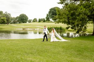 Wedding couple posing for photos on a scenic golf course with water features.