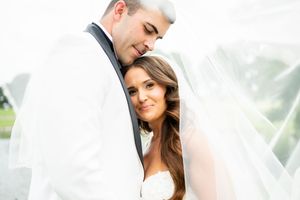 A tender wedding portrait showing a couple embracing under a white veil.