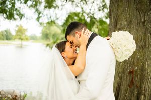 Intimate wedding moment captured under a large tree with sunlight filtering through.