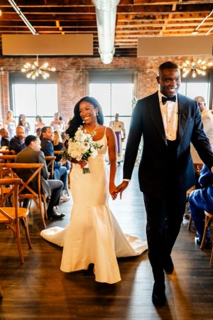 Wedding party dancing and celebrating in a modern brick-walled reception venue.