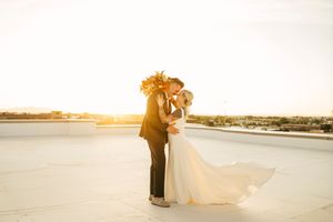 Romantic sunset silhouettes of a couple on their wedding day by the water.