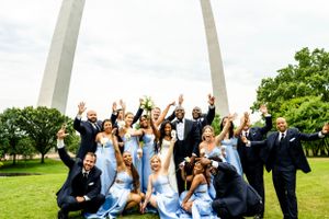 Wedding party celebrates joyfully outdoors with the St. Louis Arch as a backdrop.