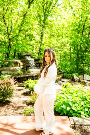 Maternity photos in lush garden setting with soft natural lighting.