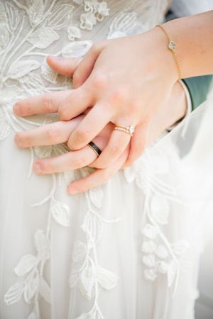 Close-up of delicate lace details and rings on a wedding dress.