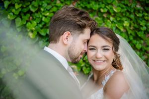 Romantic wedding portrait with lush green foliage backdrop.