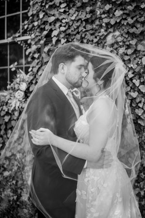Black and white intimate moment between newlyweds under a flowing veil.