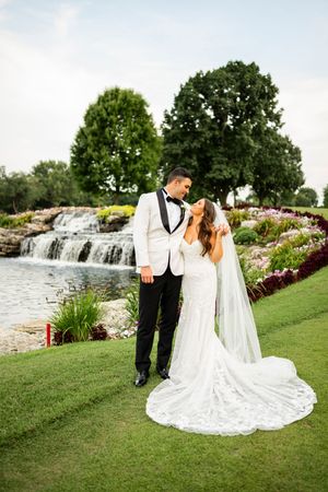 Wedding couple posing by cascading waterfall in landscaped garden setting.