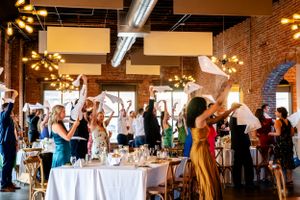 Wedding reception dance floor filled with guests in blue and white attire at an industrial-style venue.