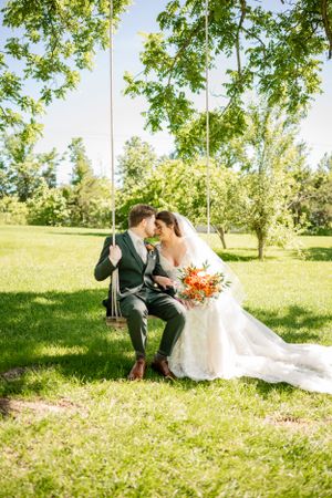 Wedding couple sharing intimate moments on grassy hillside with bright sunlight.