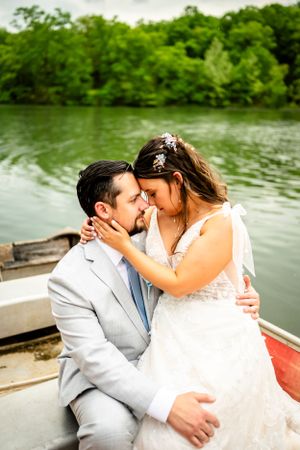 Wedding couple sharing romantic kisses in boat by lakeside.