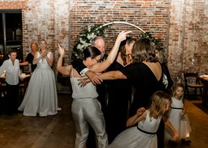 Wedding party dances and celebrates at reception in industrial brick venue.