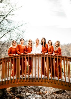 A joyful moment captured in black and white on a rustic bridge surrounded by trees.