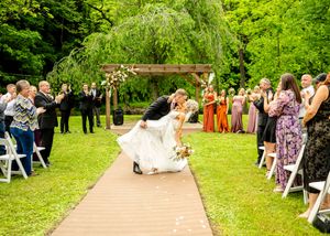 A joyful wedding ceremony moment under a wooden arch with guests looking on.
