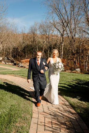 Newlyweds celebrate with raised arms under decorated gazebo during outdoor ceremony.