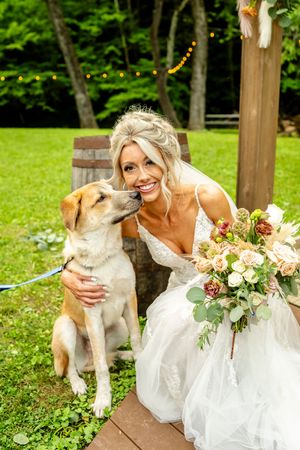 A heartwarming moment between a bride in white and her friendly dog in a garden setting.