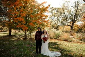 Wedding couple embracing outdoors during golden hour with fall foliage in the background.