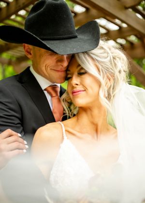An intimate moment captured under a pergola with western wedding attire.
