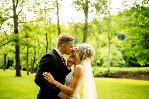 A romantic wedding portrait in a lush green park setting.