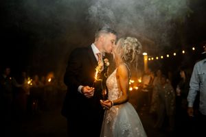 A dreamy nighttime wedding photo with string lights and atmospheric smoke.