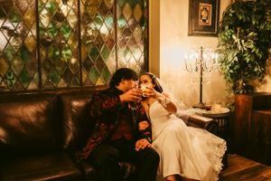 Wedding couple lounging in an elegant room with diamond wall patterns and chandelier lighting.