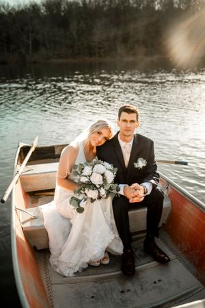 Romantic boat photoshoot at sunset with white floral bouquet accents.