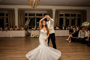 Wedding reception dance floor filled with guests celebrating under elegant chandeliers.