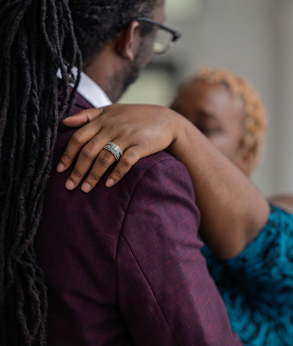 Male/female couple, female hand on male shoulder showing engagement ring