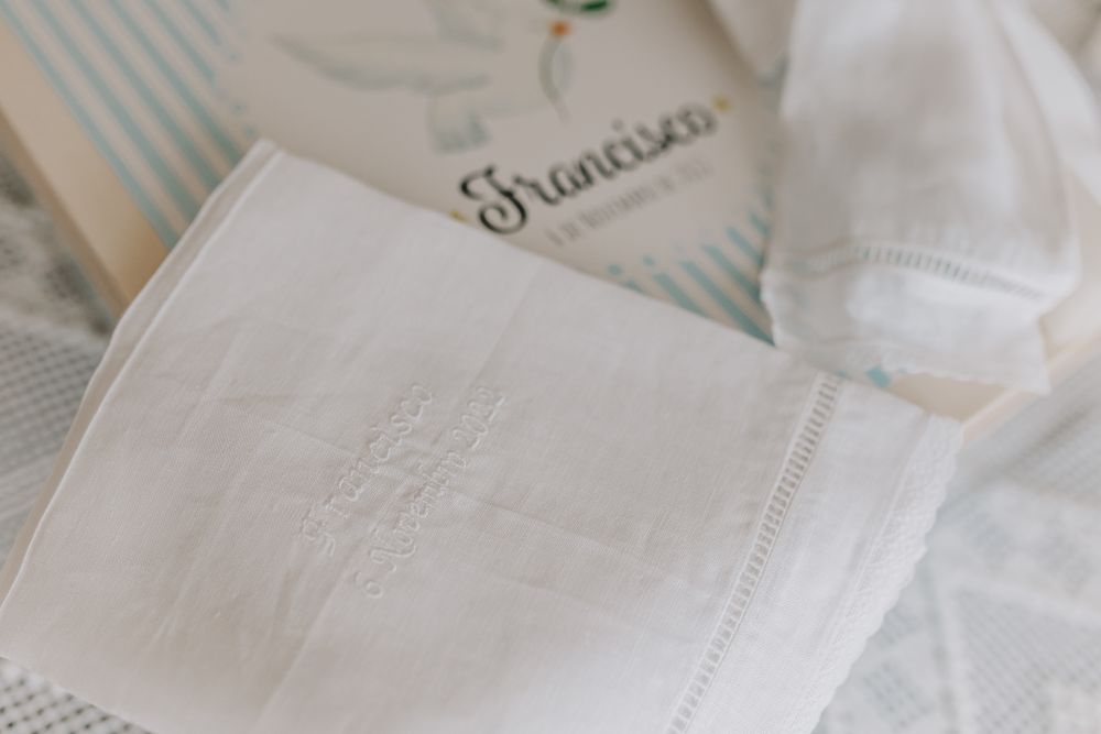 White embroidered linen cloth beside a Francisca branded box on a lace-covered surface.