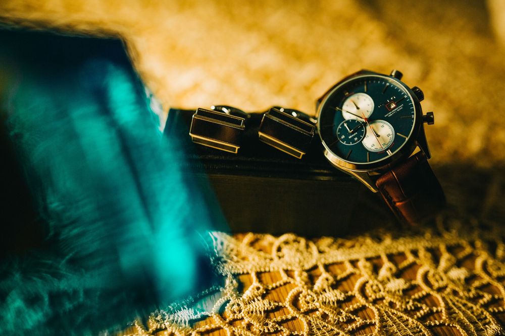 Elegant chronograph wristwatch with cufflinks displayed on a decorative surface.