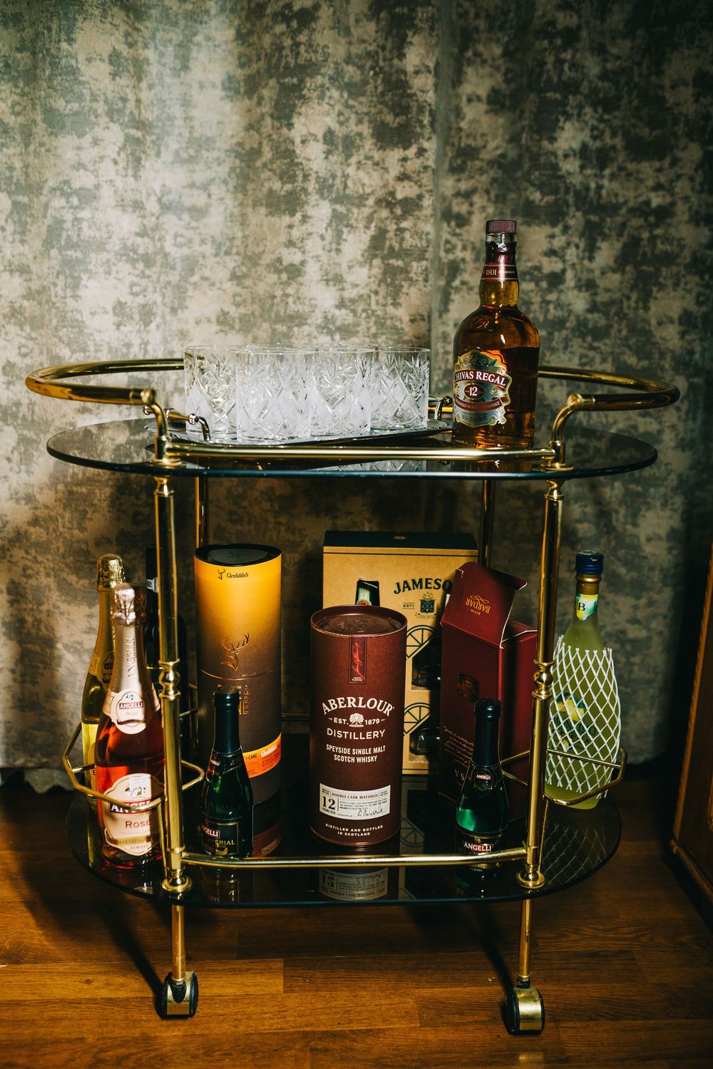 Gold bar cart with whiskey bottles including Aberlour and Jameson for a wedding celebration.