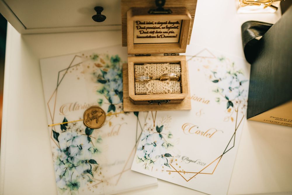 Wedding invitations with floral watercolor design and gold geometric borders with wooden ring box.